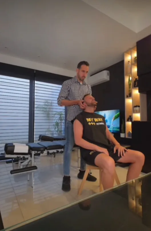 Gastón Mola realizando un ajuste cervical a un paciente sentado en el consultorio.